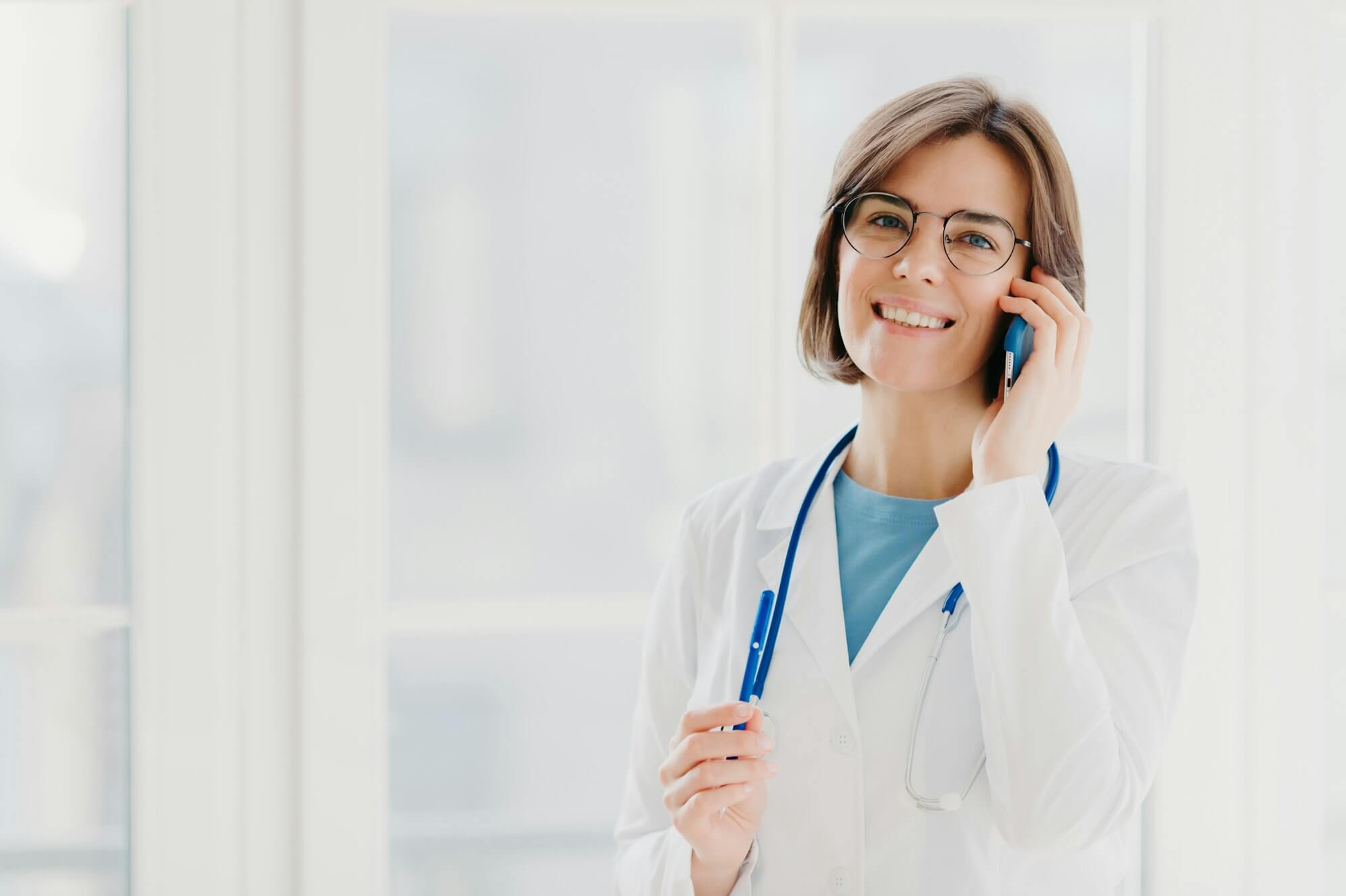 positive-woman-doctor-consults-patient-via-cellphone-looks-gladfully.jpg